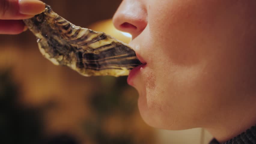 Woman eating raw oyster at the restaurant for dinner. High quality 4k footage