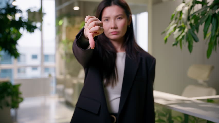 Bad result feedback negative sign displeased sad Asian business woman Chinese Korean Japanese girl businesswoman student employee manager worker in office thumb down no dislike gesture problem fail