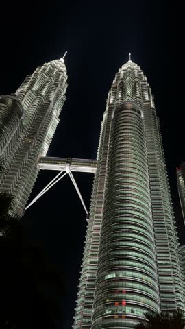 a beautiful low angle view of Petronas Twin Towers at night interlinked skyscrapers in Kuala Lumpur, Malaysia. a stunning view of white illuminated Petronas Twin Towers