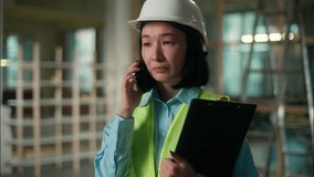 Sad dissatisfied Asian woman female inspector engineer in safety helmet talking mobile phone Chinese Korean Japanese girl building construction industry problem conflict cellphone conversation upset - Powered by Shutterstock - Get 15% off with code: PIKWIZARD15