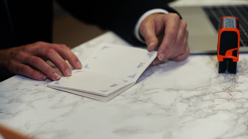 Customs worker stamping approved seal in UK passport, entry permission granted