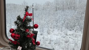 Small Christmas tree with red ribbons is sitting on a table. The tree is surrounded by red ornaments in train restaurant dining car railroad transit connection on ground - Powered by Shutterstock - Get 15% off with code: PIKWIZARD15
