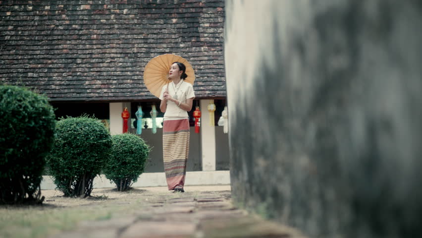 Young woman in traditional Thai dress walking near Wat Lok Molee temple in Chiang Mai, Thailand