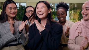 Laughing successful Japanese woman worker female receives greeting congratulation from multiethnic women females girls business coworkers businesswomen greet clapping hands applause inside office room - Powered by Shutterstock - Get 15% off with code: PIKWIZARD15