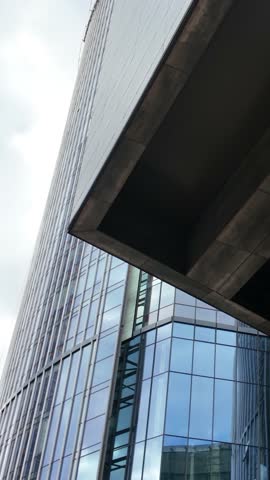 Contemporary office tower with reflective glass facade partially framed by concrete elements and structural columns.