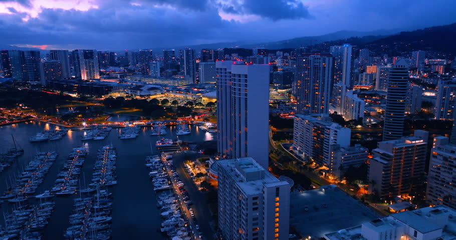 Magic scenery of the lively city at dusk. Switched on lights in the urban area. Yacht club, streets and buildings in the evenings lights. Aerial view on Honolulu, Hawaii, USA.