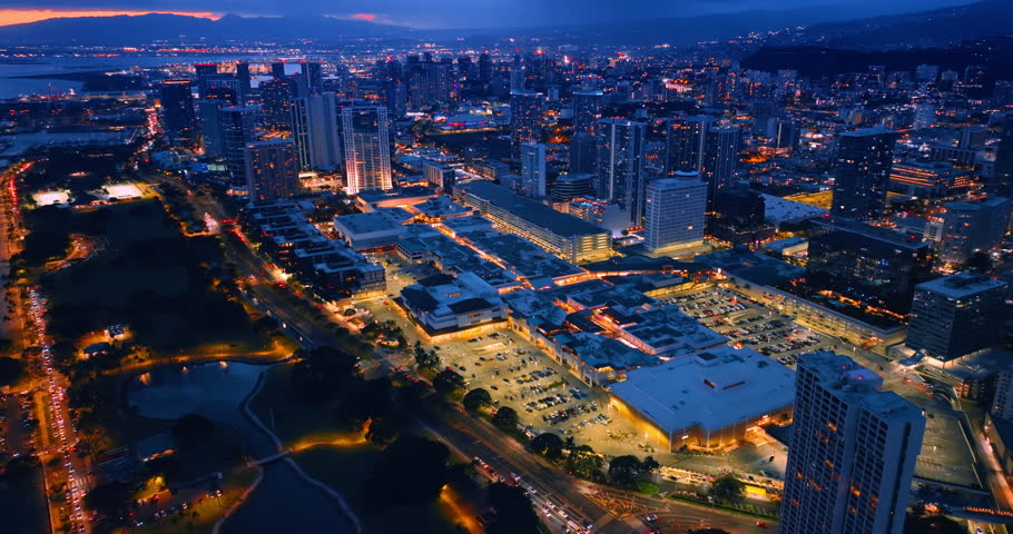 Stunning illumination of Honolulu, Hawaii, USA at dusk. Drone footage over the city full of dazzling lights.