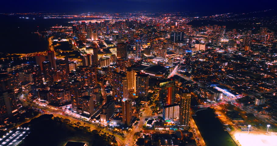 Jaw-dropping scenic view of the modern city at night. Approaching dazzling downtown of Honolulu, Hawaii, USA. Aerial perspective.