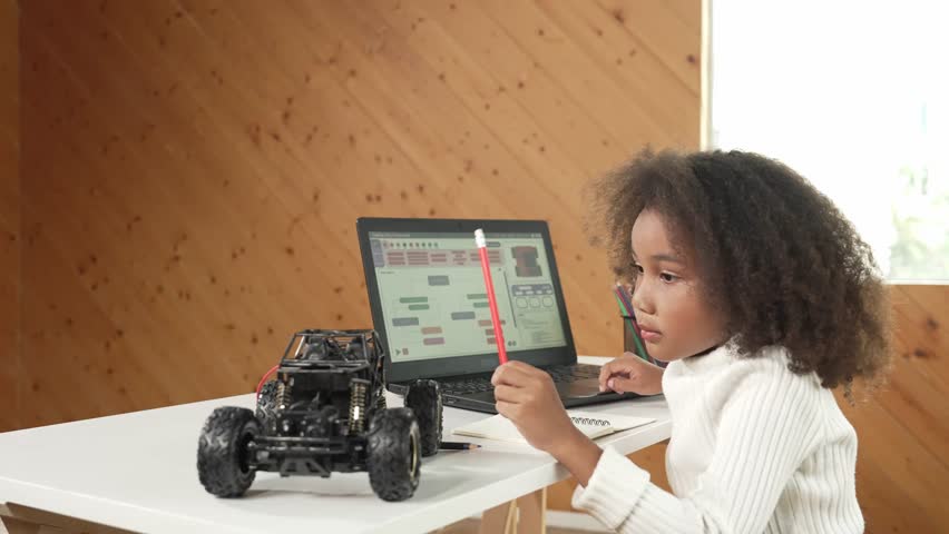 African girl pointing at car model structure while work on laptop. Student inspect at STEM education class. Panorama shot of Clever child using laptop to write programing engineer code. Erudition.