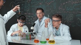 Closeup of girl hand pick biochemical test tube to prepare for working. Smart teacher and group of happy diverse children doing experiment at blackboard with theory in STEM science class. Edification - Powered by Shutterstock - Get 15% off with code: PIKWIZARD15