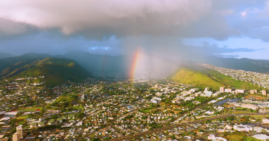 Honolulu Hawaii on a sunny day with rain clouds and a bright rainbow. Aerial view of the residential area of Manoa.