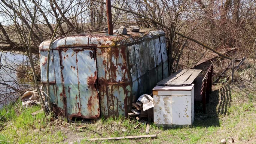 Weathered trailer resting beside river during springtime renewal