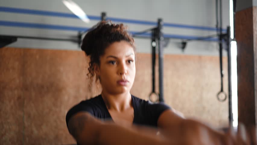 Determined African American female athlete with curly hair in bun performing controlled kettlebell swing with intense focus in modern fitness facility 