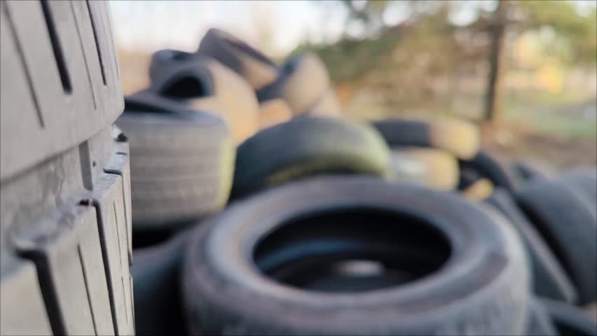 Car Tire Rubber Dump. Pile of Old Car Tyres Storage. man throws used car tires into a landfill. Car tires for recycling. Environment Disaster Concept. Slow motion