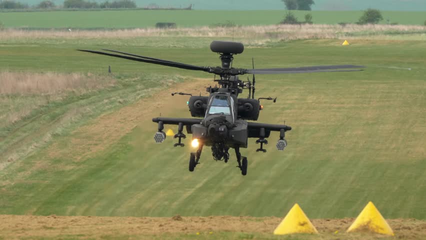 British army Boeing Apache Attack Longbow helicopter gunship AH2 AH64E AH-64E AAC in flight and hovering close to a grass runway