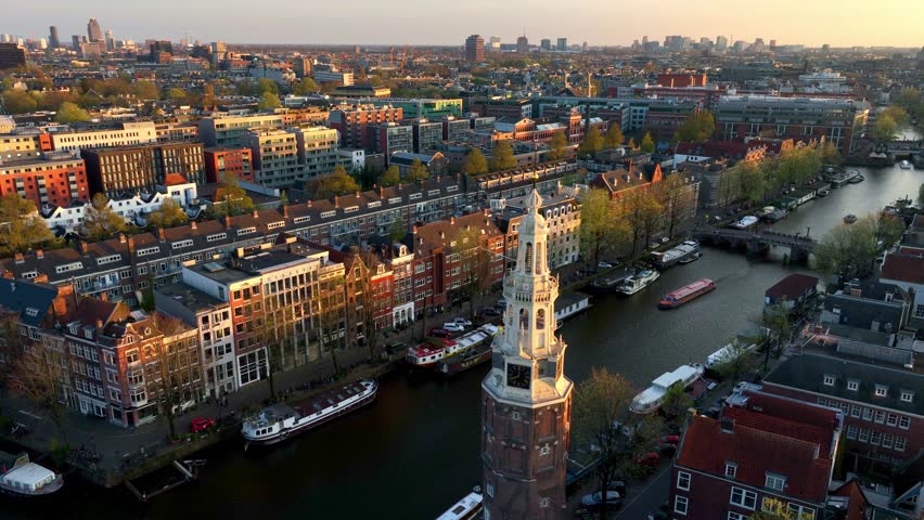 drone view of Amsterdam, capital of Netherlands, Dutch city of Amsterdam at sunset, historic district in downtown Amsterdam with a medieval tower
