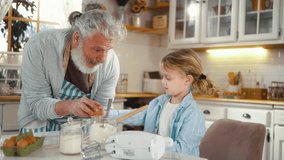 Cheerful grandfather and his cute little grandson are having fun and laughing, making pancakes in the kitchen. Grandpa teaches a little boy to crack an egg while they make pancake batter at home - Powered by Shutterstock - Get 15% off with code: PIKWIZARD15