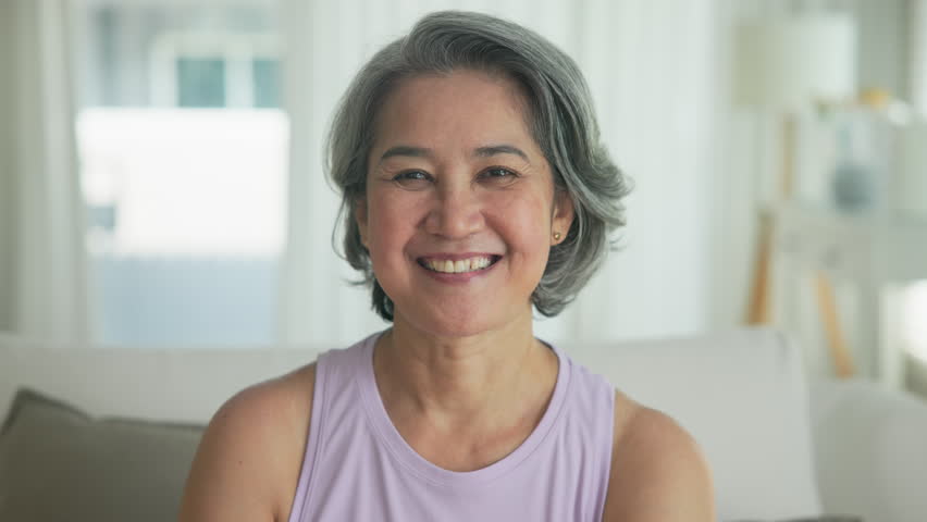 Asia adult active aged people middle age grey hair mom old female joy smile front view look at camera happy face mental health care sit relax at home sofa elder aging life asian single mum parent day.