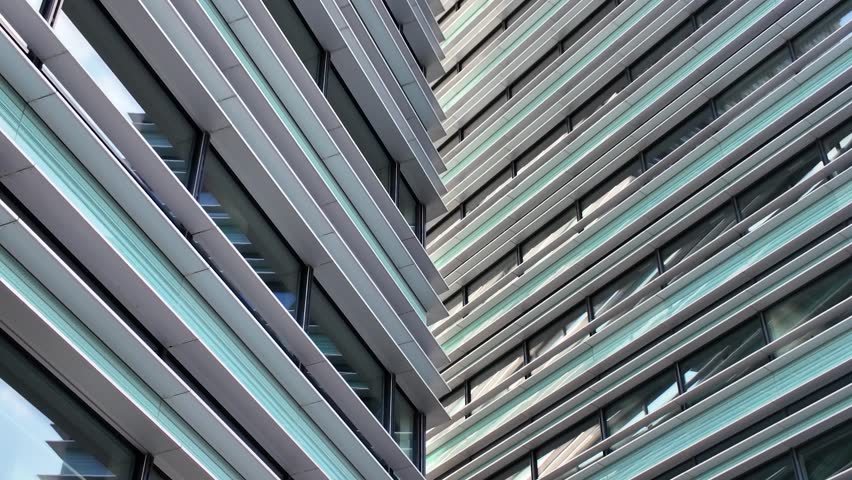 Contemporary architectural design of a modern office building featuring glass and metal facade under clear blue sky.