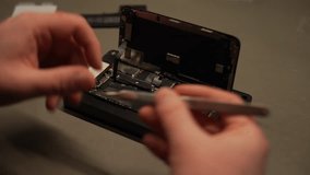 Close-up of repairman hands using tweezers, carefully detaching components from disassembled smartphone in repair workshop. Concept of professional electronics repair and maintenance in service center - Powered by Shutterstock - Get 15% off with code: PIKWIZARD15