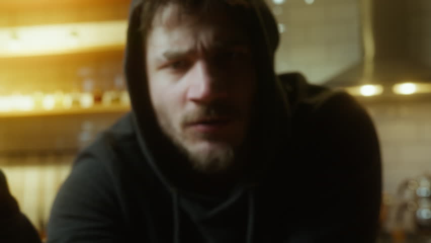 Motivated Young Man Showing Phone Screen with Work Hard Play Hard Message in Dimly Lit Room