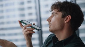 Closeup man recording voice message by cellphone sitting workspace. Serious businessman talking in cellphone loudspeaker in modern office. Handsome entrepreneur dictating voicemail audio note indoors. - Powered by Shutterstock - Get 15% off with code: PIKWIZARD15