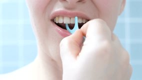 Young woman brushing teeth with disposable dental floss close-up against the background of blue tiles in the bathroom. - Powered by Shutterstock - Get 15% off with code: PIKWIZARD15