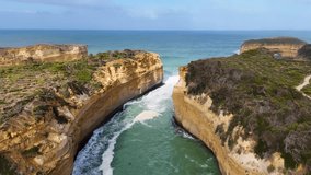 Drone footage captures the rugged cliffs and turquoise waters of Loch Ard Gorge, Port Campbell, under clear skies - Powered by Shutterstock - Get 15% off with code: PIKWIZARD15
