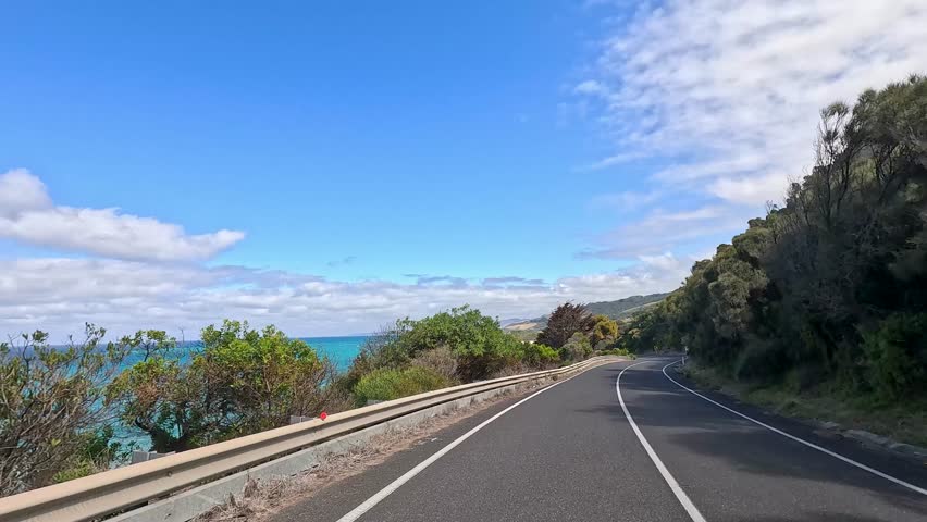 A 14-second video captures a serene drive along the Great Ocean Road, showcasing coastal views and lush greenery under clear skies