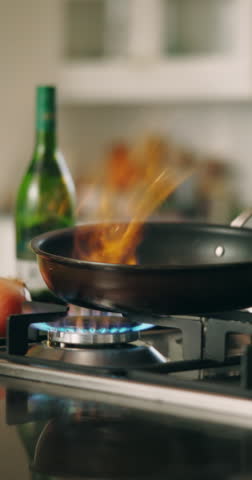Recipe, hand and pan in kitchen with flame, culinary skills and technique process. Man, chef and fire in skillet for gourmet meal, cooking food and add seasoning for cuisine preparation in restaurant