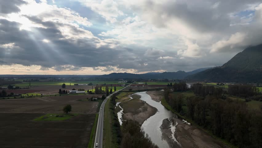 Aerial River Landscape: Fields, Mountains, and Cloudy Skies of British Columbia