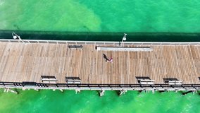 aerial footage of a man running on the Ventura Pier surrounded by vast green ocean water at Ventura beach in Ventura California USA - Powered by Shutterstock - Get 15% off with code: PIKWIZARD15