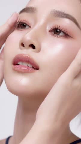 Vertical footage beautiful young Asian woman with healthy facial skin isolated over white background for skincare commercial product advertising. Slow motion shot.