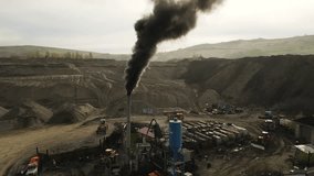 Heavy machinery operates at a mining site, releasing dark smoke into the air as the sun rises. Trucks and equipment are busy in the rugged terrain, showcasing industrial activity. - Powered by Shutterstock - Get 15% off with code: PIKWIZARD15