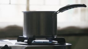  A slow-motion of pouring water into stainless-steel pot on a lit stovetop against blur background - Powered by Shutterstock - Get 15% off with code: PIKWIZARD15