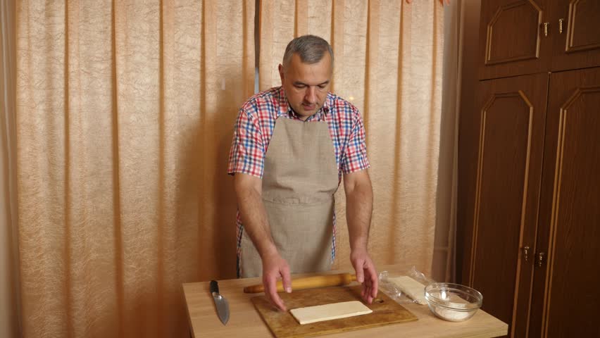 A man prepares pies from dough and sweet filling. Cooking homemade dishes.