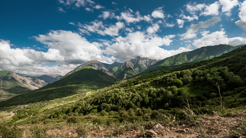 Timelapse mountains. Green slopes at foot of Greater Chimgan. Wild beautiful nature without people, cloudy sky. Time lapse clouds moving fast. Concept of freedom and calmness in unity with nature