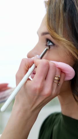close up eyes Makeup, Make up in process , beautician applies makeup eyeshadows in bright professional studio, Beautiful woman face, Hand of master in beauty salon, wedding preparation