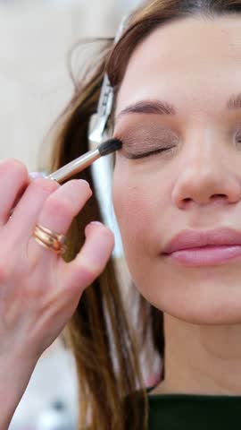 close up eyes Makeup, Make up in process , beautician applies makeup eyeshadows in bright professional studio, Beautiful woman face, Hand of master in beauty salon, wedding preparation