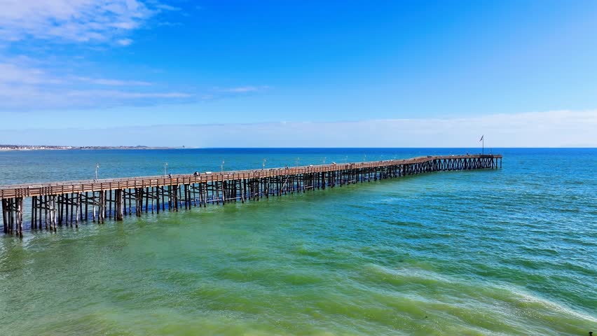 Aerial footage of the Ventura Pier with vast blue ocean water and waves at Ventura beach in Ventura California USA	