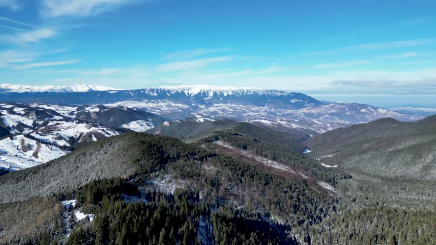 The view of Piatra Craiului Mountains covered with snow as seen from Bucegi Mountains on a sunny winter day in the city of Brasov in central Romania