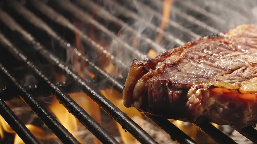 Smooth movement. Golden crusted mouth watering T-bone steak is sprinkled with coarse salt and finished on grill. Juicy, flavorful masterpieces that are meat lover's dream come true, template for title