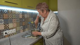 Senior woman mashes boiled potatoes for mashed potatoes for lunch at home in the kitchen. Grandmother cooking food - Powered by Shutterstock - Get 15% off with code: PIKWIZARD15