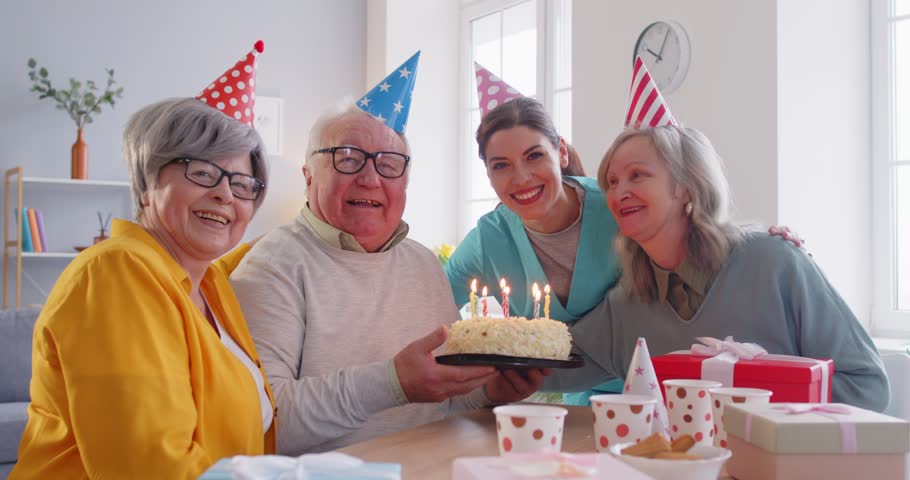 Happy Birthday party cake, candles blowing out fun, elderly with nurse, caregiver, carer, support worker, active seniors in social recreational friendship club, retirement house, retired people center