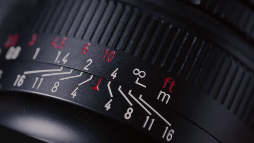 Close up: film photography lens shifts focus. Moving distance scale on vintage film photography lens during focusing. Fingers adjusting DSLR Lens