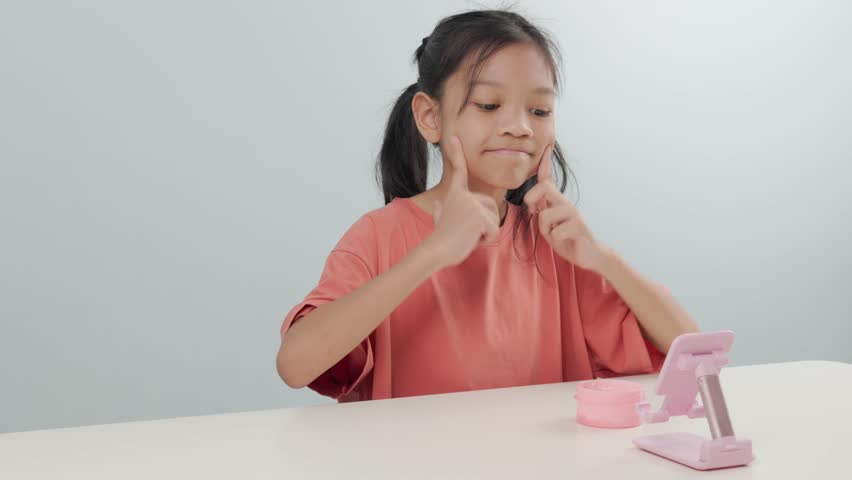 A cute elementary school age kid girl is applying white cream to nourish and care for her face. with different poses. She smiled brightly and is happy to take care of herself. White background.