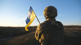 Ukrainian army soldier holding waving flag of Ukraine. Portrait of man in military uniform and helmet lifted up flag in hill. Victory against russian aggression. Invasion resistance concept. Slow mo - Powered by Shutterstock - Get 15% off with code: PIKWIZARD15