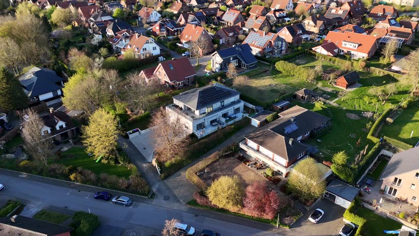 Solar panels on roof of high class residential apartment during sunset time. Aerial top down flyover shot. Suburb district in spring season. Spring season with green grass in garden. Quiet
