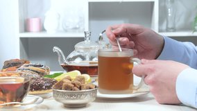Male hands of an elderly man pouring tea from a teapot into a cup before drinking a cup of tea. Close-up. Slow motion. - Powered by Shutterstock - Get 15% off with code: PIKWIZARD15