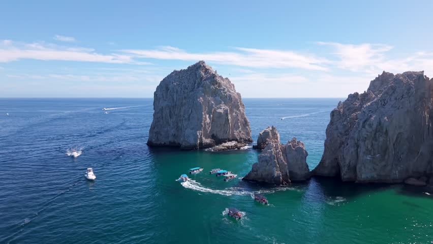 Daytime aerial over Cabo San Lucas facing the famous Arch while boats are sailing in the ocean]